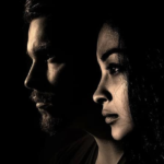 Dark background, man and woman looking in same direction