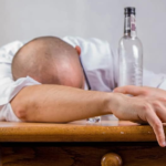 Man collapsed on table with empty bottle near his head